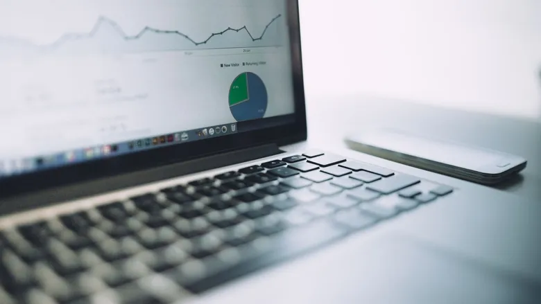 Laptop showing an analytics dashboard with charts next to a smartphone and notebook