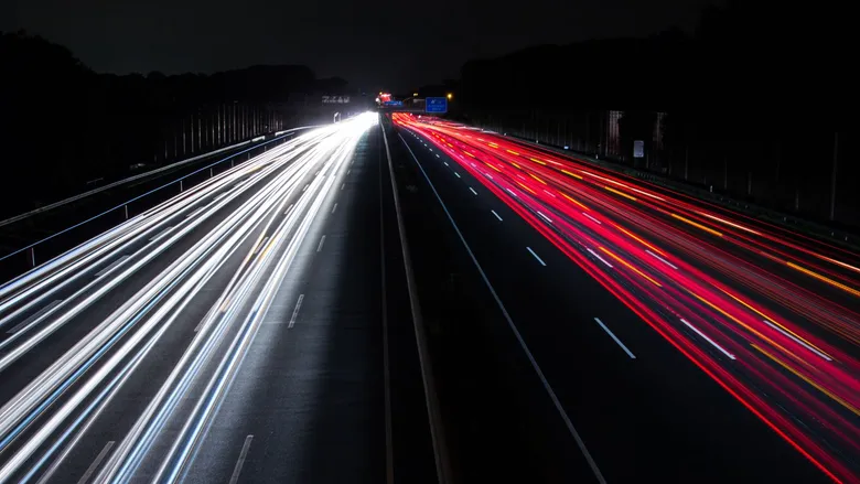 Long-exposure light trails of traffic on a highway at night