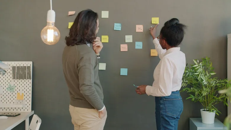 Team brainstorming around a wall covered in colorful sticky notes