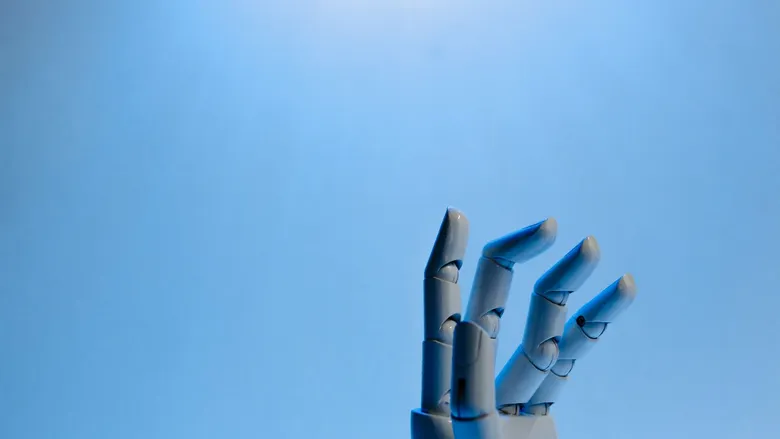 Robotic hand with articulated fingers reaching upward against a blue background