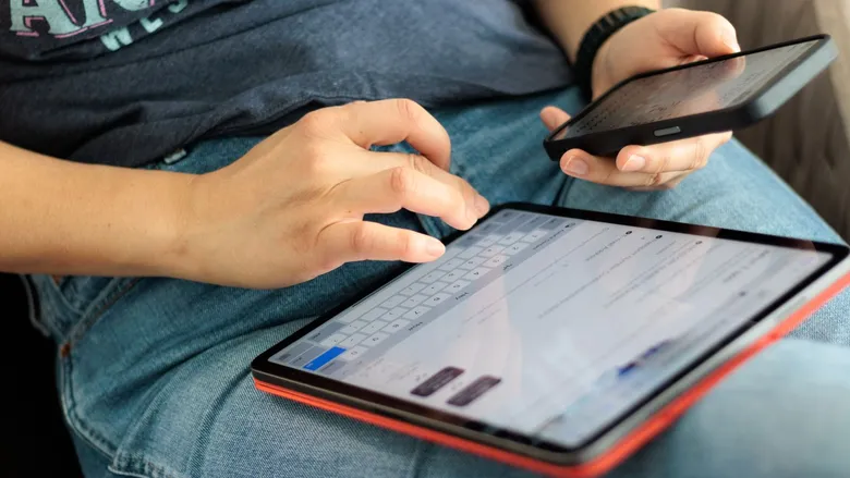 Close-up of hands using a smartphone and a digital tablet at the same time