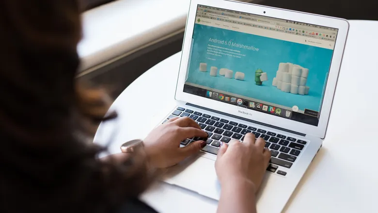 Businesswoman at a table working on a laptop with a web page open