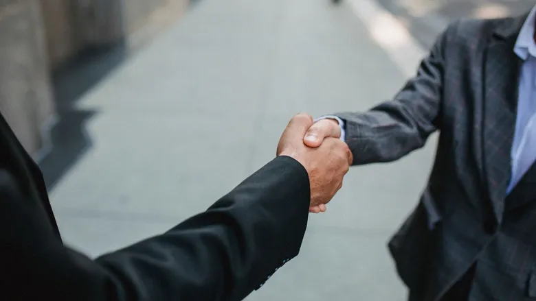 Two businessmen in suits shaking hands outdoors